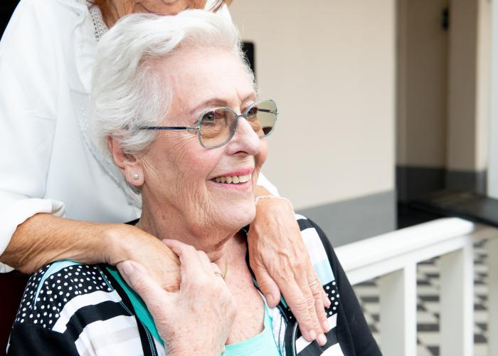 Oude vrouw 2 handen op haar schouders